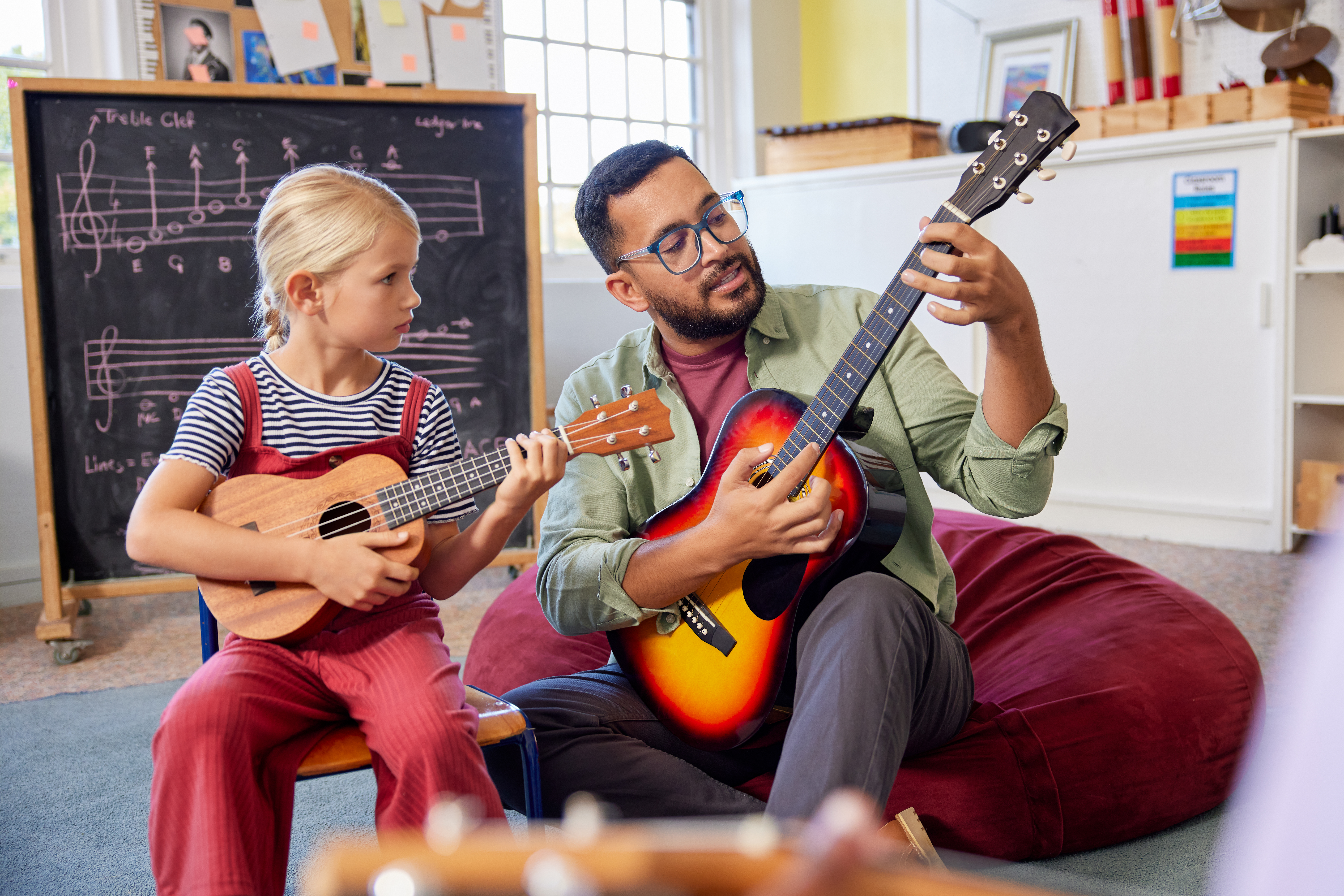 Music tutor teaches a young student the guitar.